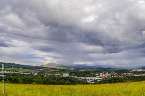 Landscape view with rainbow of the town of Valasske Mezirici during the rain in the hills on the horizon where the sun shines into the landscape. photo