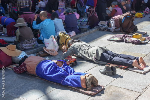 People praying in prostration in front of Jokhang temple in Lhasa on Barkhor square, Tibet photo