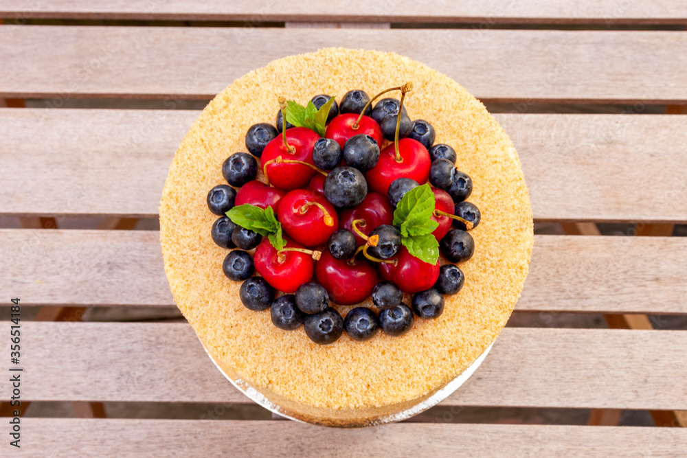 Cake with walnuts, prunes, and honey with a delicate buttercream decorated with fresh blueberries and cherries Cake with walnuts, prunes, and honey with a delicate buttercream decorated with fresh blueberries and cherries