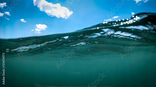 Underwater image of clear blue sky and rolling sea wave