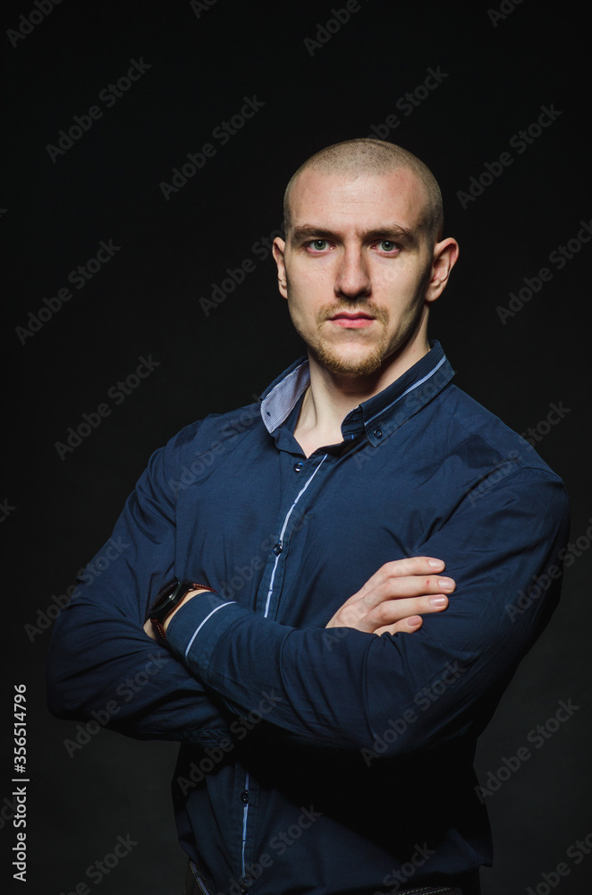 A stylish, bald young man stands on a dark background in the category. Business, Finance
