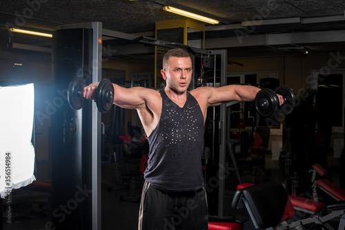 A young athletic guy is engaged in fitness in the gym. Fitness, bodybuilding