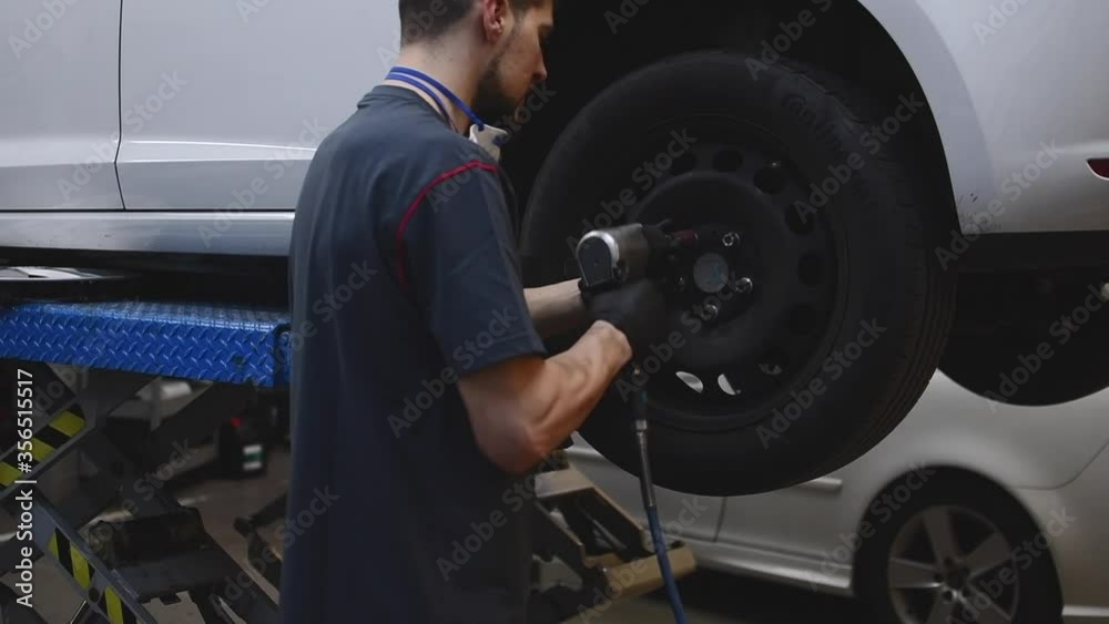 mechanic placing the bolts of a wheel in a car 2 mechanic placing the bolts of a wheel in a car 2