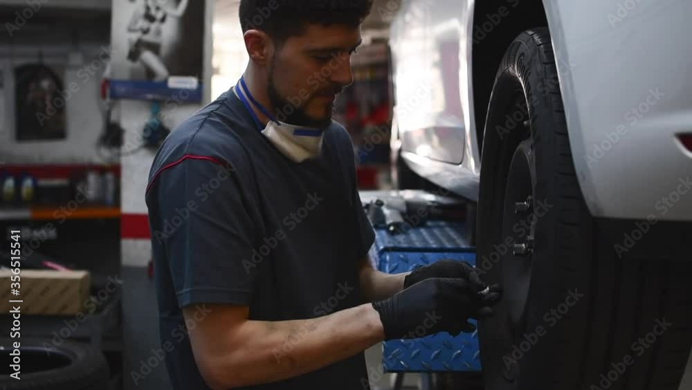 mechanic placing the bolts of a wheel in a car mechanic placing the bolts of a wheel in a car
