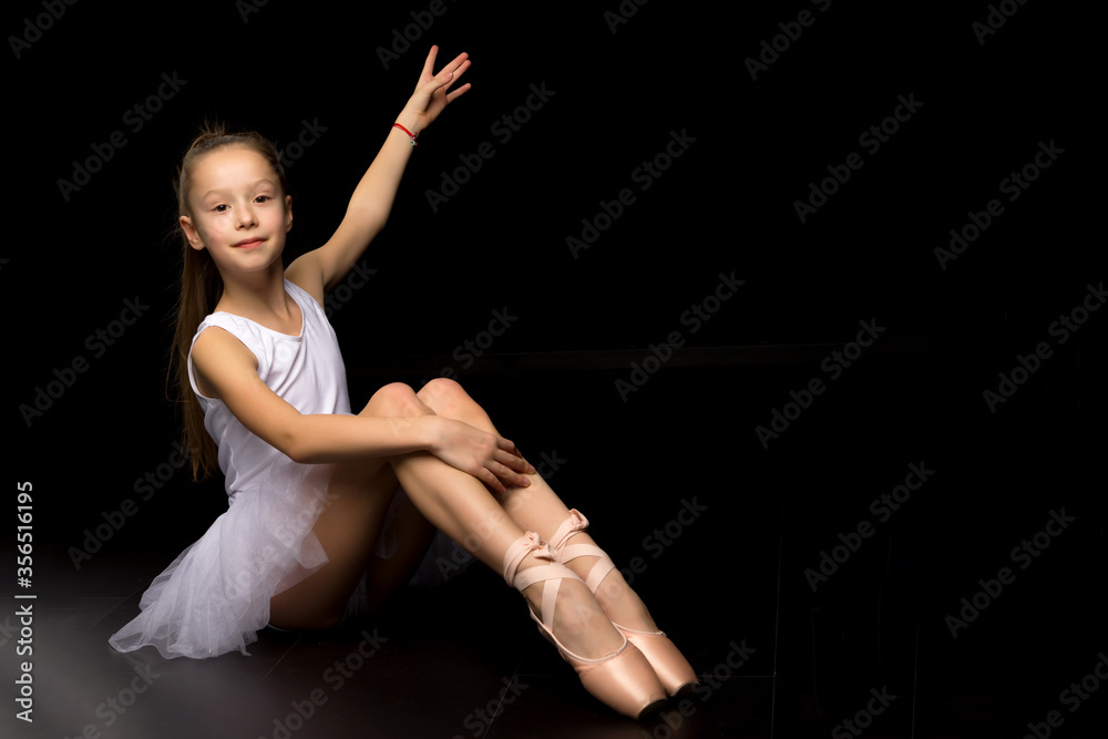 Beautiful little ballerina on a black background. dance concept.