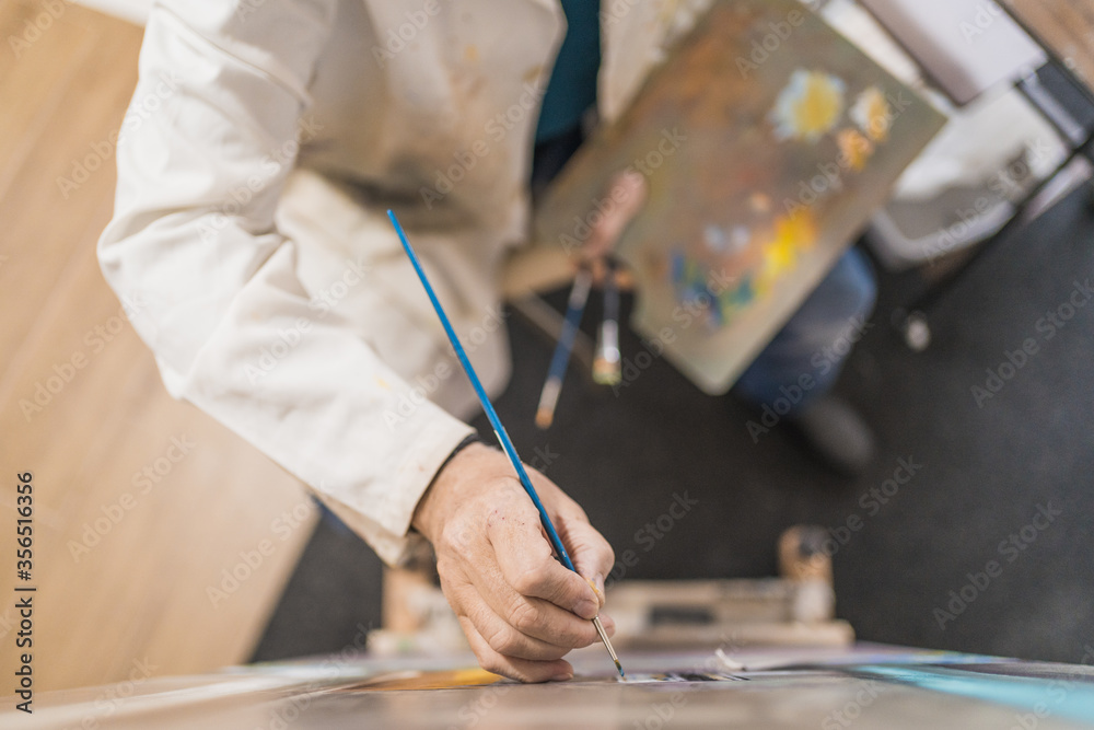 Aged man painting picture with brush Aged man painting picture with brush