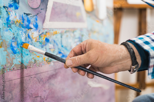 Aged man painting picture with brush photo