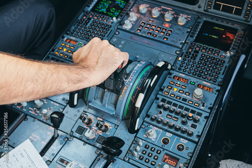 From above crop anonymous male aviator pushing lever on dashboard while piloting modern aircraft during flight