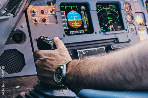 Crop anonymous male pilot performing manual control of contemporary aircraft during flight photo