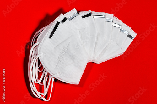 group of white masks fanned out with reusable KN95 protection index for virus protection on red background photo