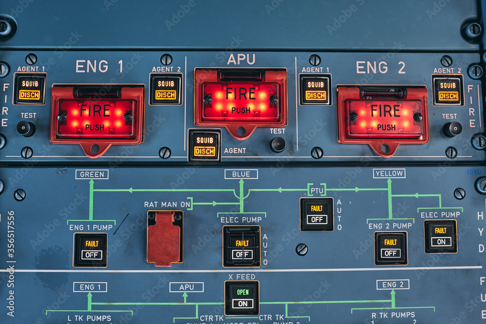 Closeup of fire buttons and warning lights on control console in cockpit of contemporary airplane