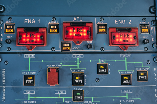Closeup of fire buttons and warning lights on control console in cockpit of contemporary airplane