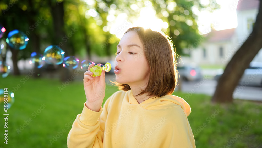 Pretty teenage girl blowing soap bubbles on a sunset. Child having fun in a park in summer. Pretty teenage girl blowing soap bubbles on a sunset. Child having fun in a park in summer.