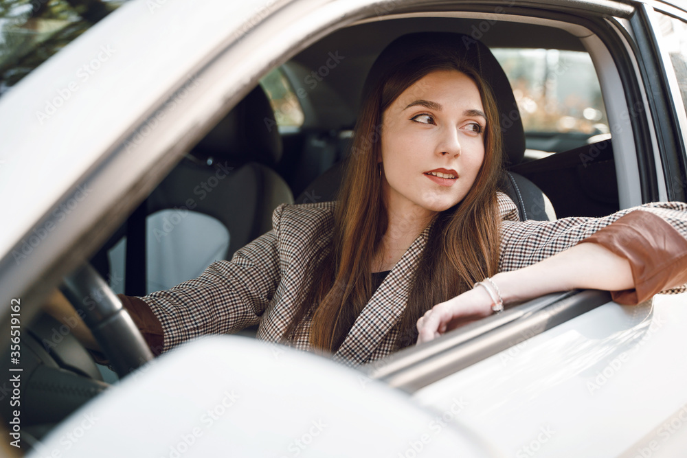 Beautiful young girl sitting behind the wheel of a luxury car