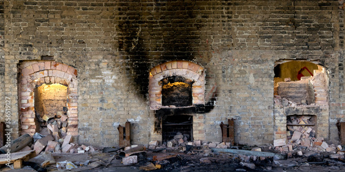 Wide angle view of aged stone wall with destroyed furnaces and trash inside abandoned industrial factory photo