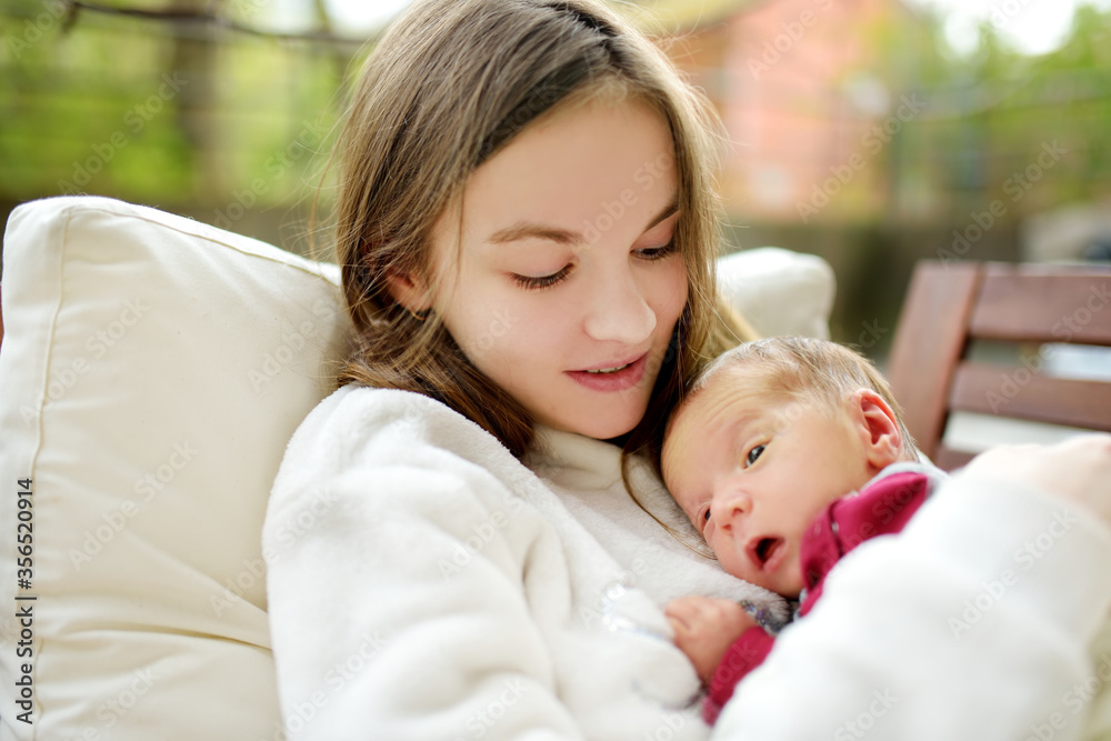 Cute big sister admiring her newborn brother. Adorable teenage girl holding her new baby boy brother. Kids with large age gap. Big age difference between siblings. Cute big sister admiring her newborn brother. Adorable teenage girl holding her new baby boy brother. Kids with large age gap. Big age difference between siblings.