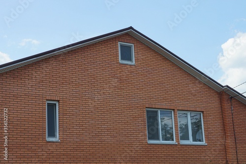 large brown brick loft of a private house with white windows against a blue sky