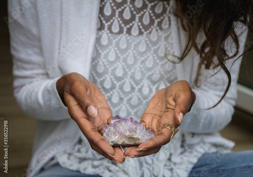 Unrecognizable ethnic female in casual outfit sitting with crystals for rituals photo