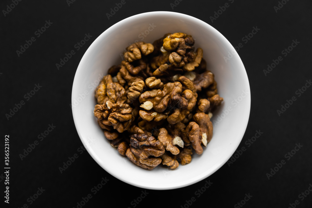 Walnut in a small plate on a black table. Walnuts is a healthy vegetarian protein nutritious food. Natural nuts snacks. Walnut in a small plate on a black table. Walnuts is a healthy vegetarian protein nutritious food. Natural nuts snacks.