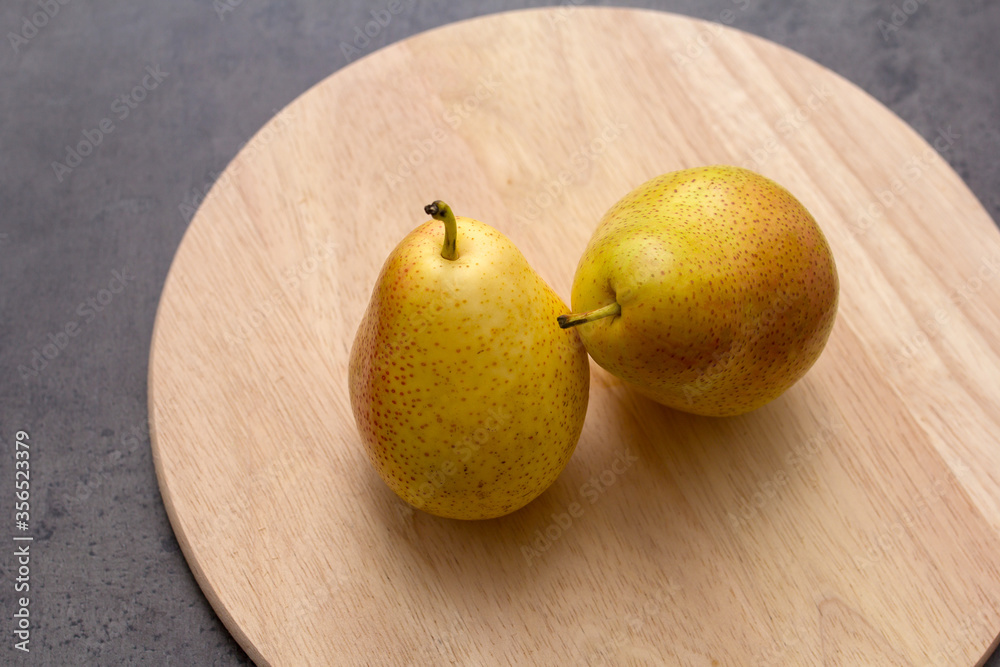 two pears on a wooden chopping Board on a dark table two pears on a wooden chopping Board on a dark table