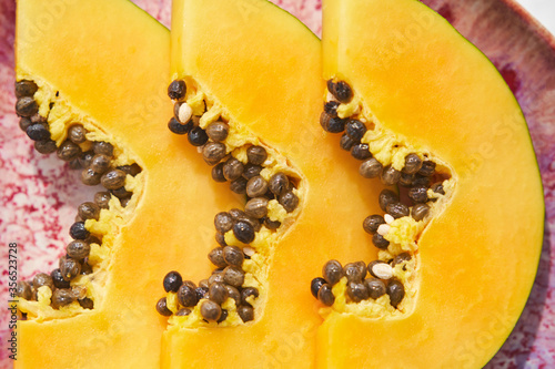 From above pieces of fresh papaya with seeds placed on plate on white background photo