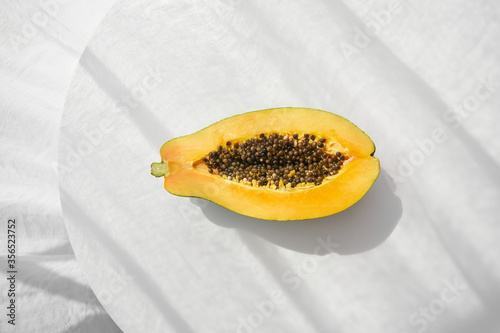 Top view of half of fresh healthy papaya with seeds placed on white table