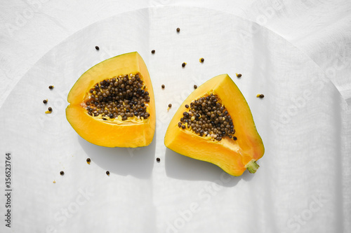 Top view of halves of fresh healthy papaya with seeds placed on white table photo