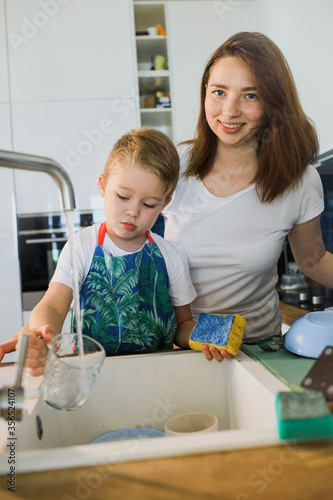 mother and son wash dishes together.