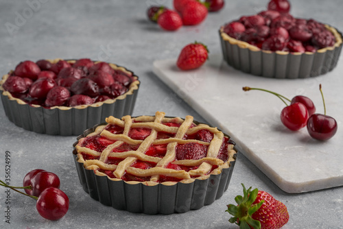 vegan tartlets with cherries and strawberries on a light gray background and marble board