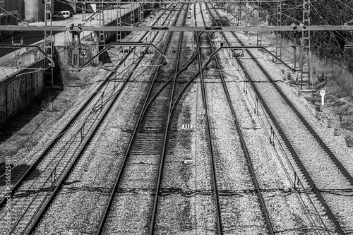 Parallel train tracks and connection between two of them, seen from a bridge. Black and white.