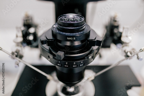 Lens of modern machine over Petri dish and manipulators during process of ovum fertilization in contemporary lab of clinic photo