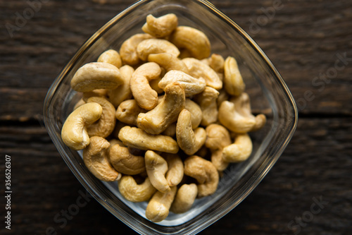 Cashew nuts in a small plate on a vintage wooden table as a background. Cashew nut is a healthy vegetarian protein nutritious food.