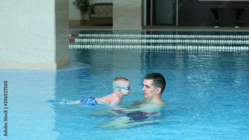 Father and son play in the pool. Father throws the son Father and son play in the pool. Father throws the son