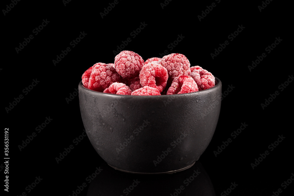 Frozen raspberries in a dark bowl on a black background. Closeup. Copy space Frozen raspberries in a dark bowl on a black background. Closeup. Copy space