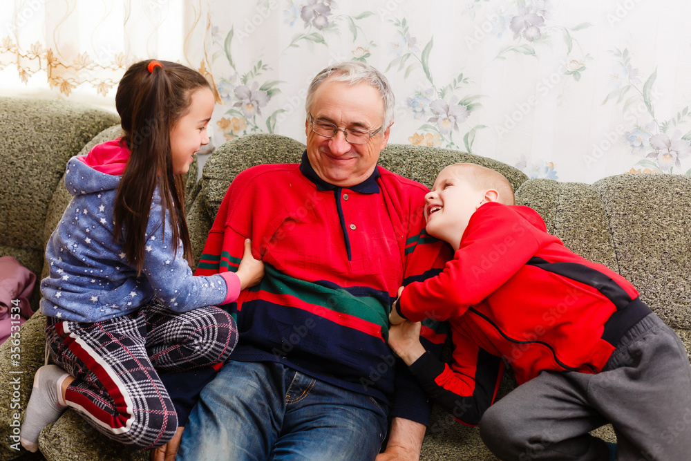 Obraz premium grandfather spends time with grandchildren in the living room