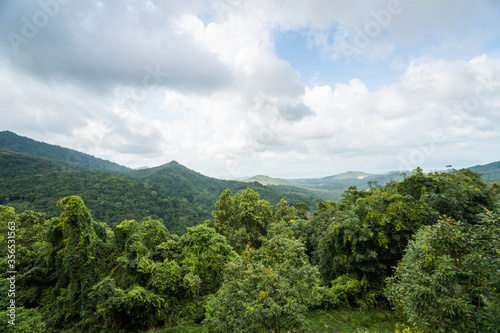 Summer tropical forest hills with a cloudy sky. Mountains and white clouds on a blue sky. Tropical summer holiday vacation concept.
