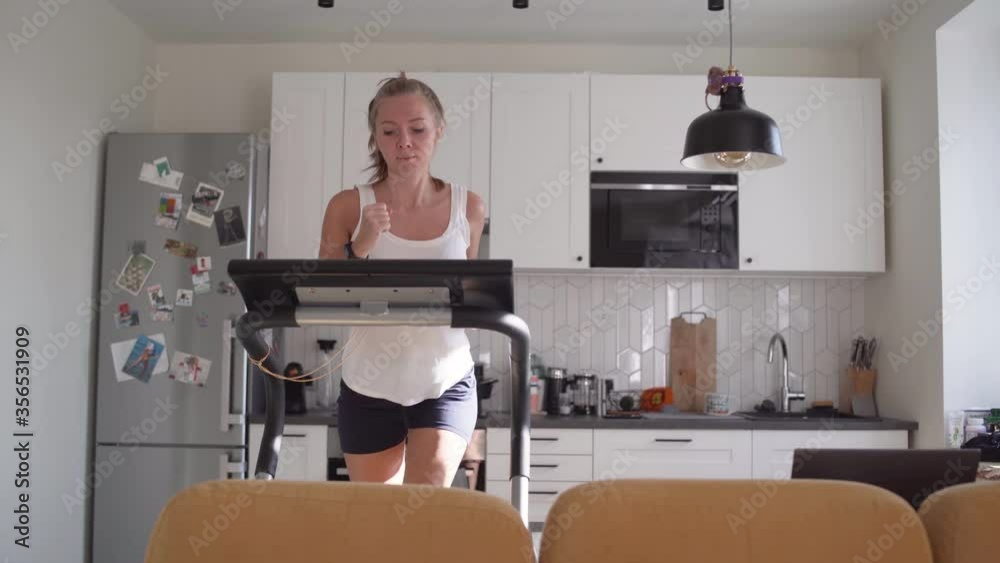 Woman running on running machine at home Woman running on running machine at home