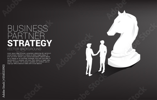 Silhouette of businessman handshake with chess piece knight. Concept of team work partnership and cooperation strategy.