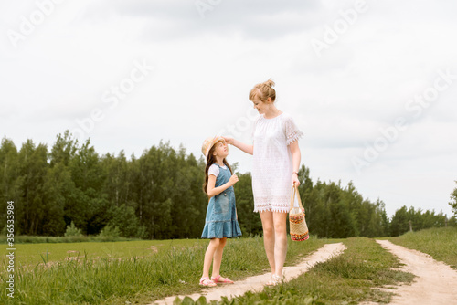 mother and daughter walking in the forest and holding hands.walk along the path. field and nature. Wicker basket. maternal love, happy childhood.