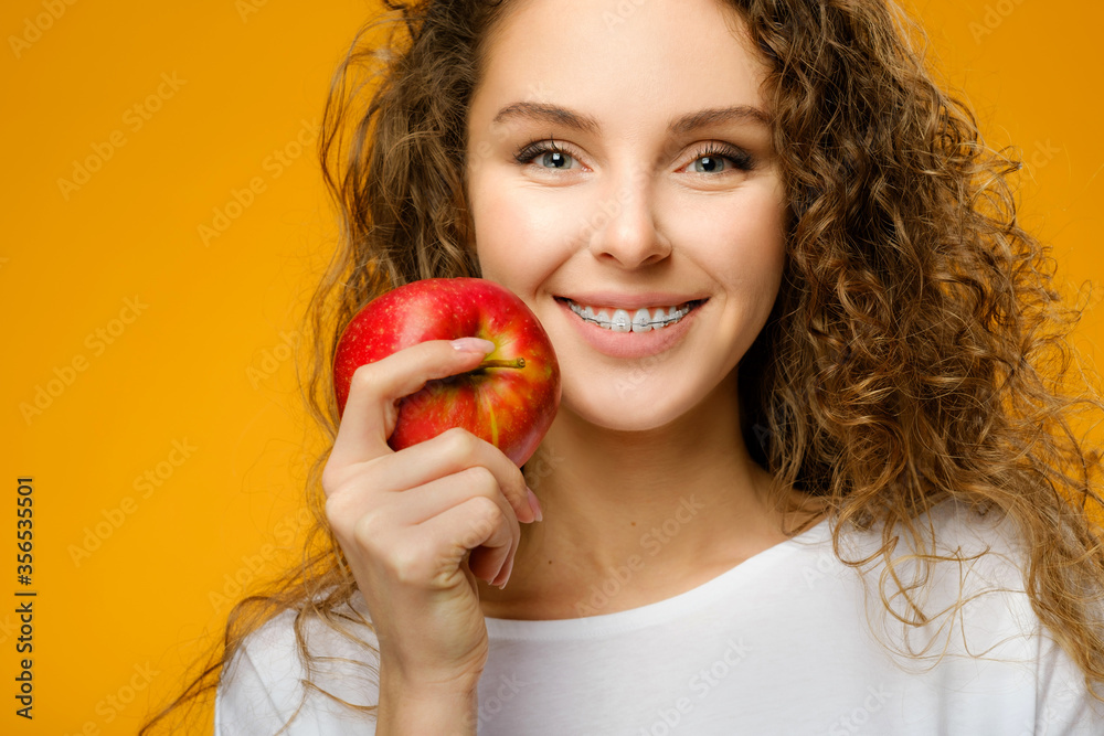 Pretty girl with dental braces on yellow background Pretty girl with dental braces on yellow background