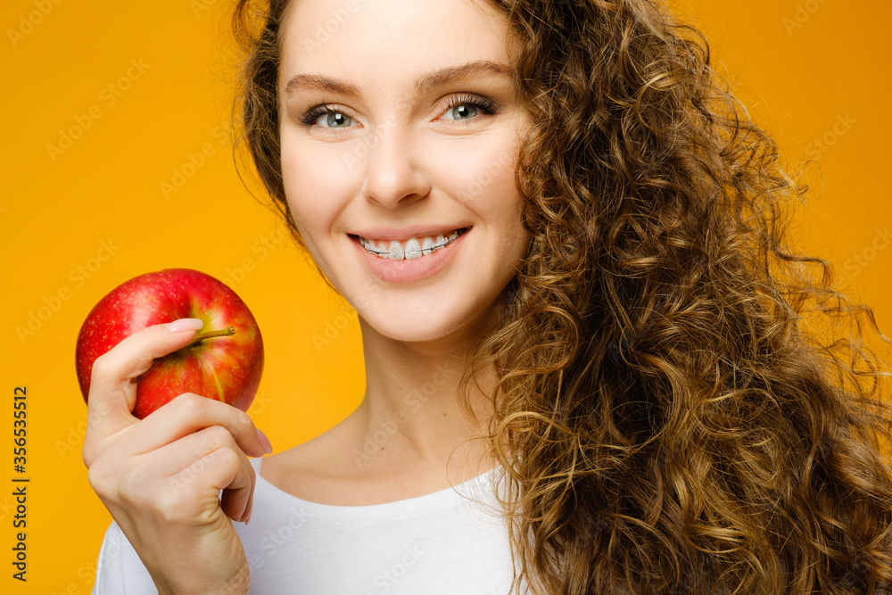 Pretty girl with dental braces on yellow background Pretty girl with dental braces on yellow background
