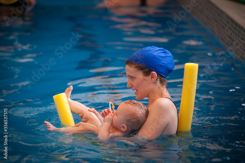Mother and 9 months old premature son photographed during a swimming lesson in a pool.