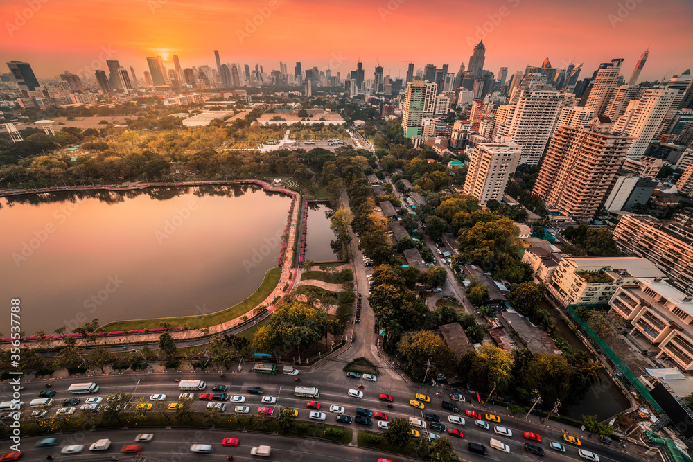 Benjakiti Public Park with a Lake, Skyscrapers and Traffic in Bangkok, Thailand at Sunset