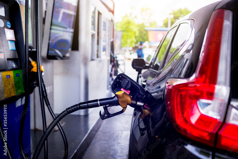 Selective focus to Petrol pump filling nozzles. Black car refueling on a petrol station. Pumping gasoline fuel in car at gas station. The concept of fuel energy.