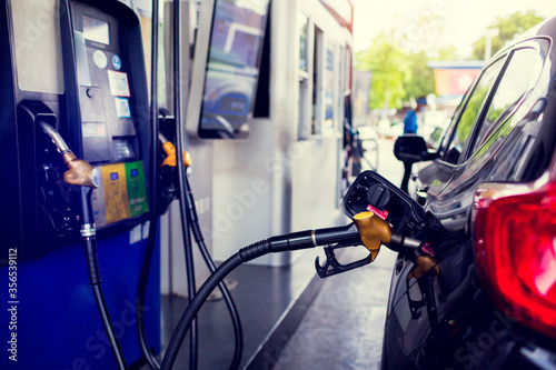 Selective focus to Petrol pump filling nozzles. Black car refueling on a petrol station. Pumping gasoline fuel in car at gas station. The concept of fuel energy.