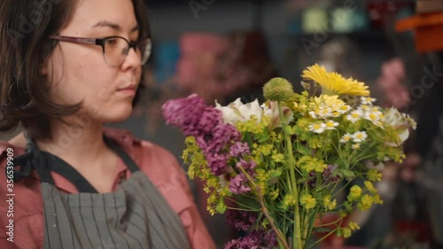 close up of woman composing a bunch of flowers. selling floral arrangement. professional florist making romantic bouquet present for selling. shop or workshop. wildflowers