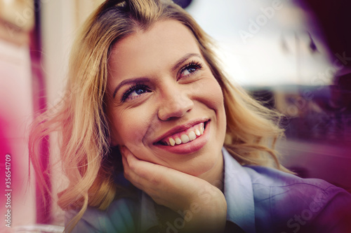 Close up portrait of young adult caucasian blonde woman smiling in day