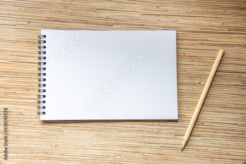 Notebook with pencil on wooden background. Cosy workspace. Top view, flat lay