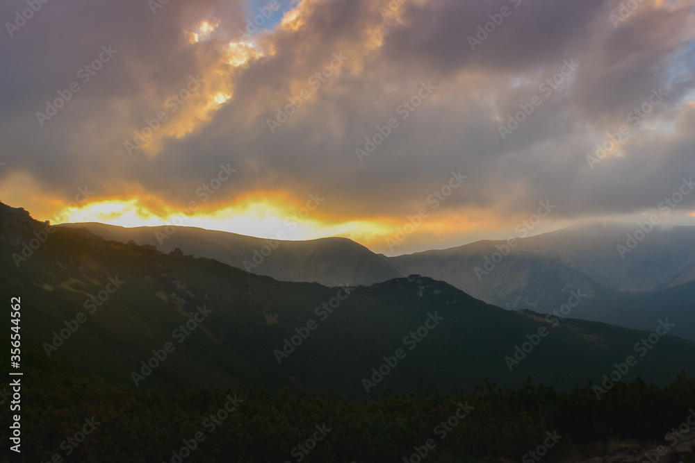 Beautiful sunset view of landscape of mountains, forest and meadows in the Carpathians in sunny cloudy weather Beautiful sunset view of landscape of mountains, forest and meadows in the Carpathians in sunny cloudy weather