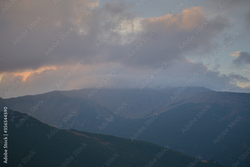 Beautiful sunrise view of landscape of mountains, forest and meadows in the Carpathians in sunny  cloudy weather